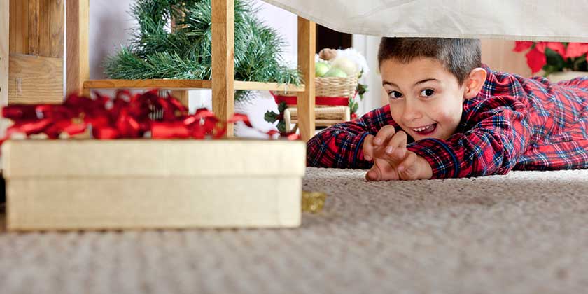Child searching under bed for Christmas Presents