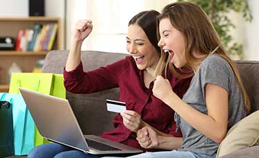 Two excited students shopping online with a laptop and credit card, celebrating great storage deals for students.