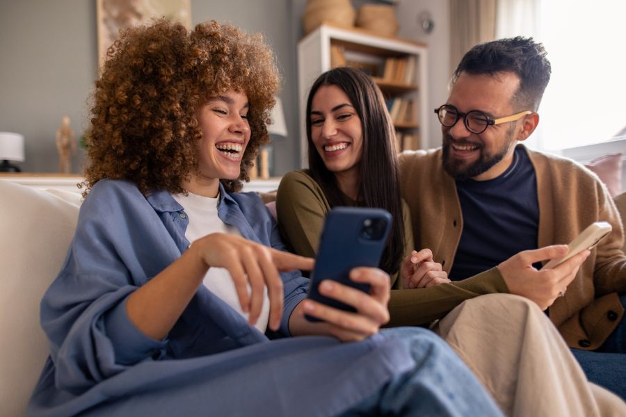 Young adults laughing and sharing content in a modern flat, illustrating Gen Z’s flexible living and use of self storage