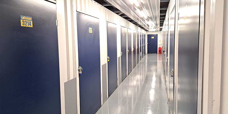 Corridor inside self storage facility with numbered blue doors and polished floors.