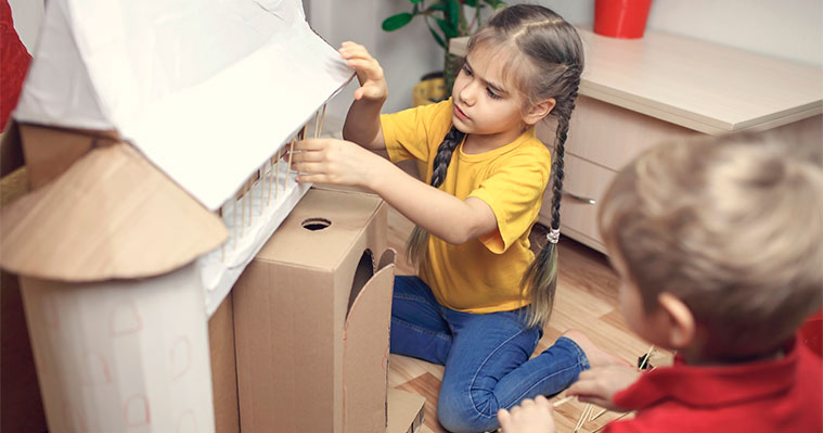 Two children making a cardboard castle