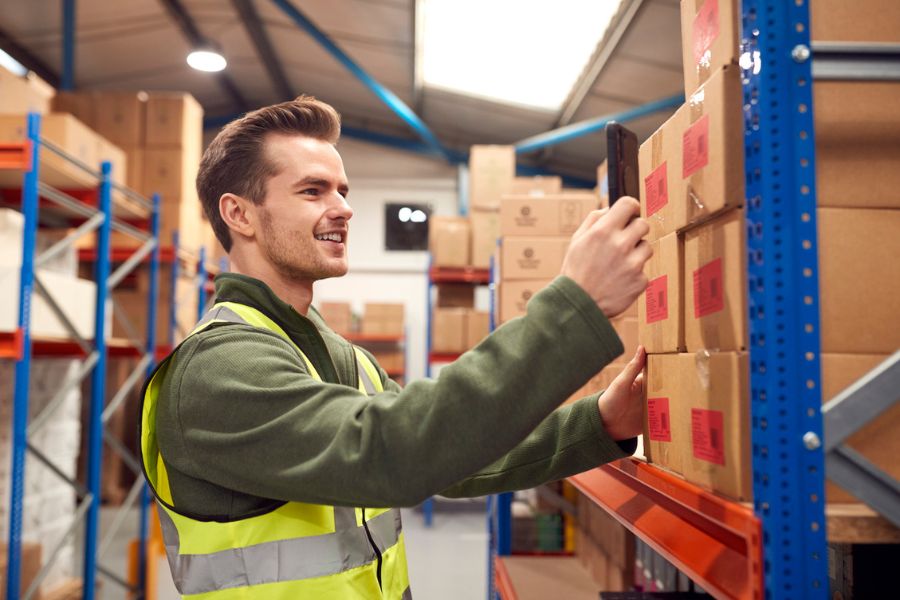 Warehouse worker scanning stock barcodes on shelves using a handheld device