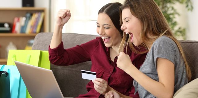 Two excited students shopping online with a laptop and credit card, celebrating great storage deals for students.