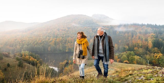 An older couple walking in a scenic autumn landscape, symbolising retirement and life transitions requiring decluttering or downsizing.