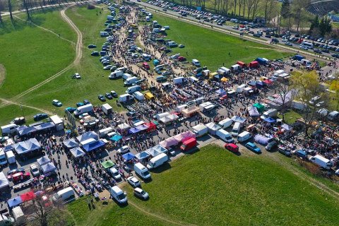 Aerial view of a busy car boot sale with stalls, vans, and crowds of people shopping on a sunny day