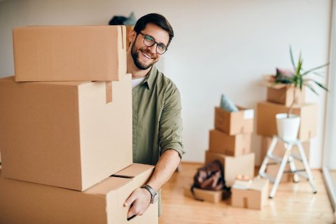 Person carrying moving boxes inside a new flat