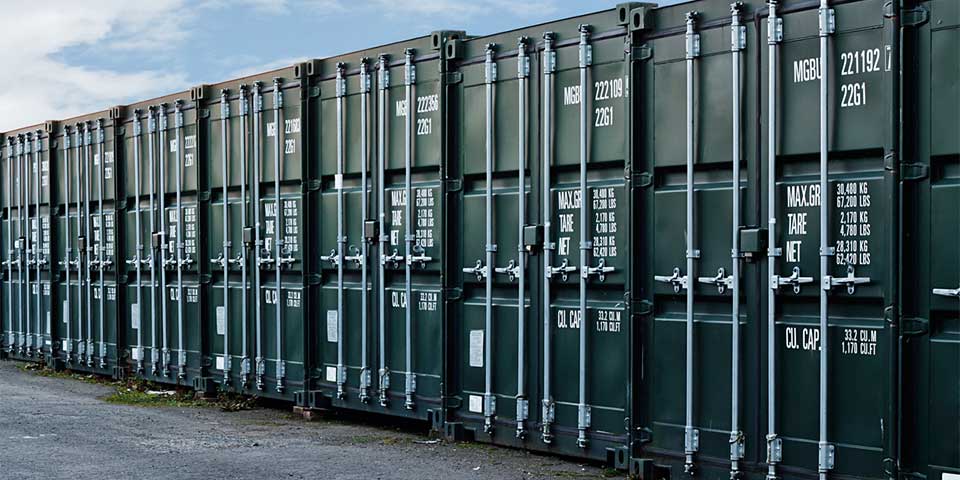Row of green container storage units with secure metal latches.