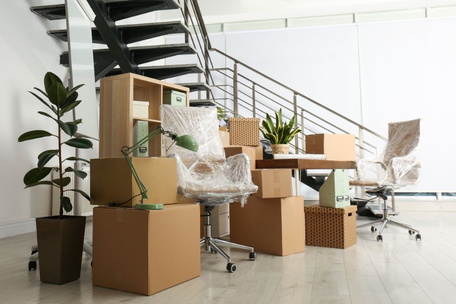Cardboard boxes and office furniture stacked near stairs on moving day