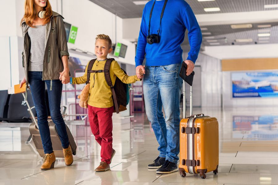 Family walking with suitcases in a travel setting, heading off on holiday
