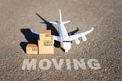 Toy airplane on pavement beside the word MOVING, symbolising international relocation and worldwide moving