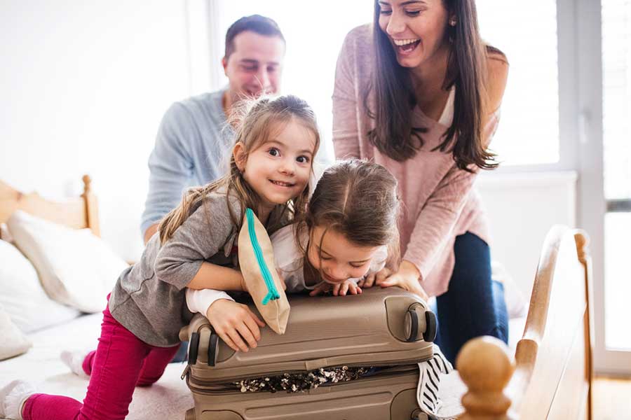 Family packing suitcases at home before summer holiday, preparing to use self storage for belongings