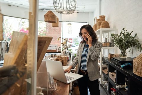 Small business owner managing online orders on a laptop inside a boutique workspace