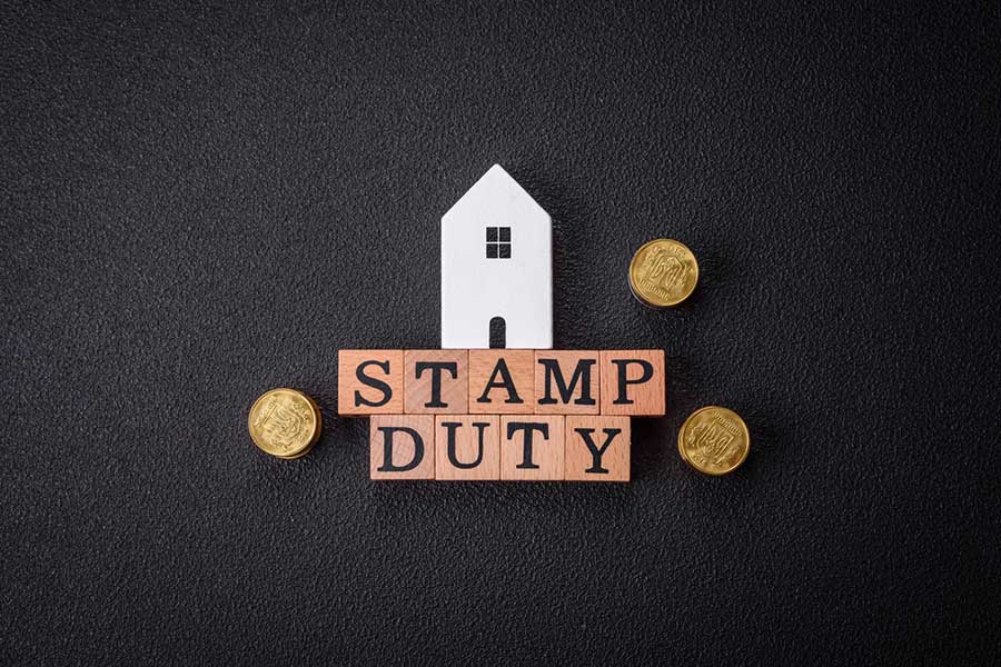 A miniature house, coins, and wooden blocks spelling "Stamp Duty."