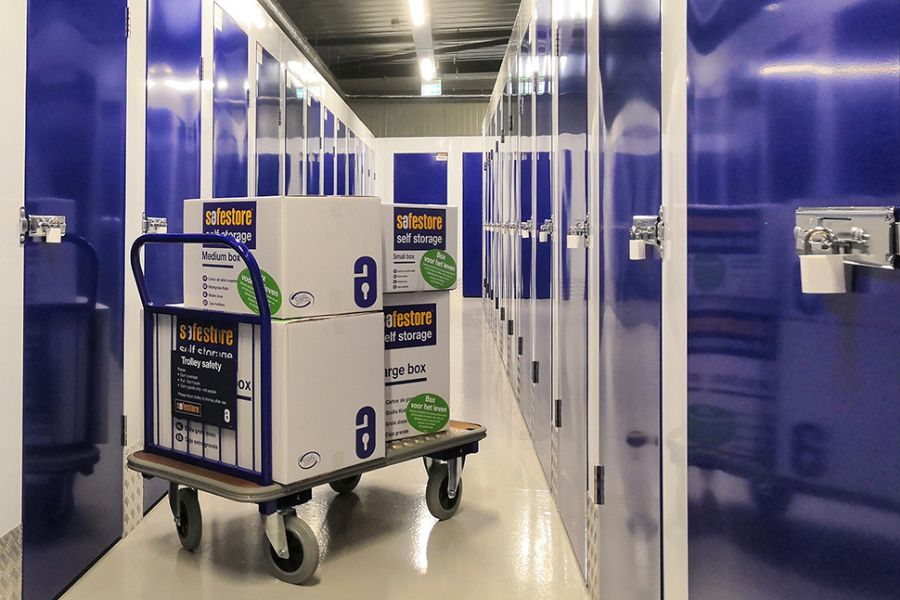 Interior hallway of a self storage facility with secure storage units, locks and a trolley with boxes
